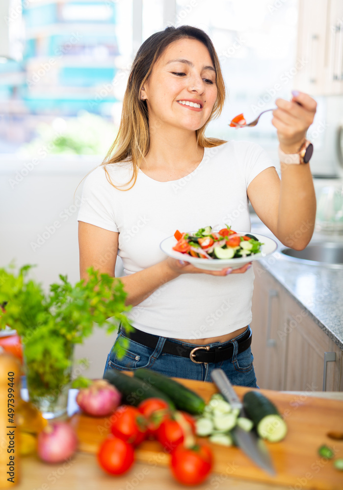 Positive female eating healthy salad with fresh vegetable