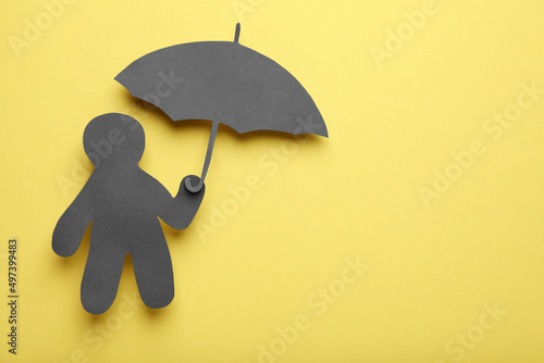 Black paper cutout of human holding umbrella on yellow background, top view with space for text. Depression concept photo