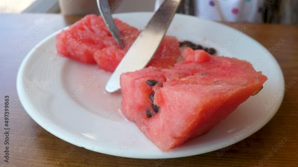Unrecognizable hand cut by knife delicious watermelon. Plate with fruit slices Unrecognizable hand cut by knife delicious watermelon. Plate with fruit slices