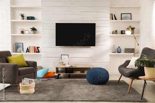Cozy room interior with stylish furniture, decor and modern TV set