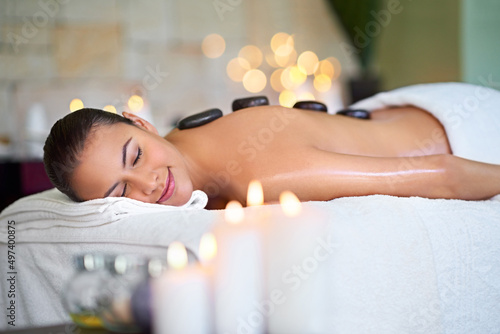 Take a vacation on our massage table. Shot of a young woman enjoying a hot stone massage at a spa.