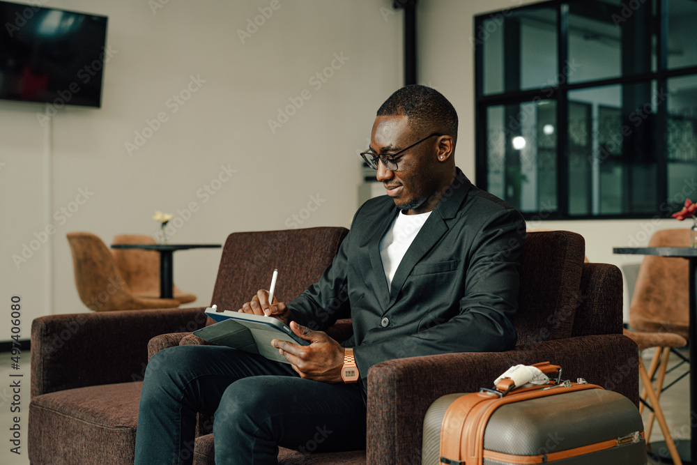 Businessman Uses tablet Waiting for a Flight, Traveling Entrepreneur Remote Work Online Sitting in a Boarding Lounge of Airline Hub. Businessman Uses tablet Waiting for a Flight, Traveling Entrepreneur Remote Work Online Sitting in a Boarding Lounge of Airline Hub.