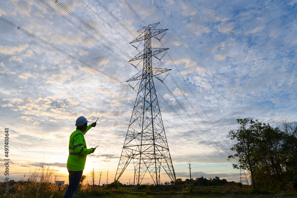 Engineer inspecting high voltage tower with radio,Engineer inspecting high voltage tower