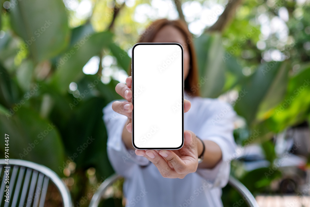 Mockup image of a woman holding and showing a mobile phone with blank white screen