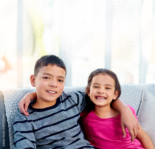 Were closer than you think. Portrait of two adorable young siblings posing with their arms around each other while relaxing on a sofa at home.
