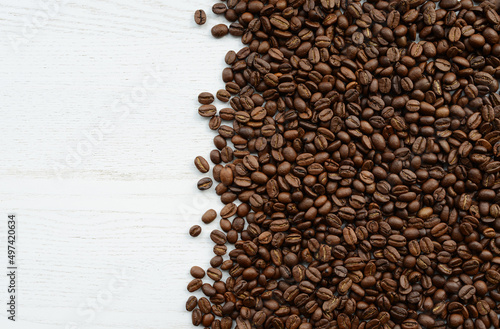 Coffee beans on a white wooden table. Roasted coffee beans on a white background, top view, copy space