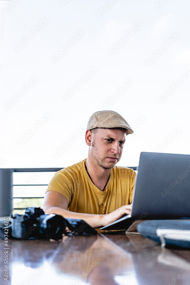 Vertical of a Caucasian man working on his laptop with an angry expression on his face. 
