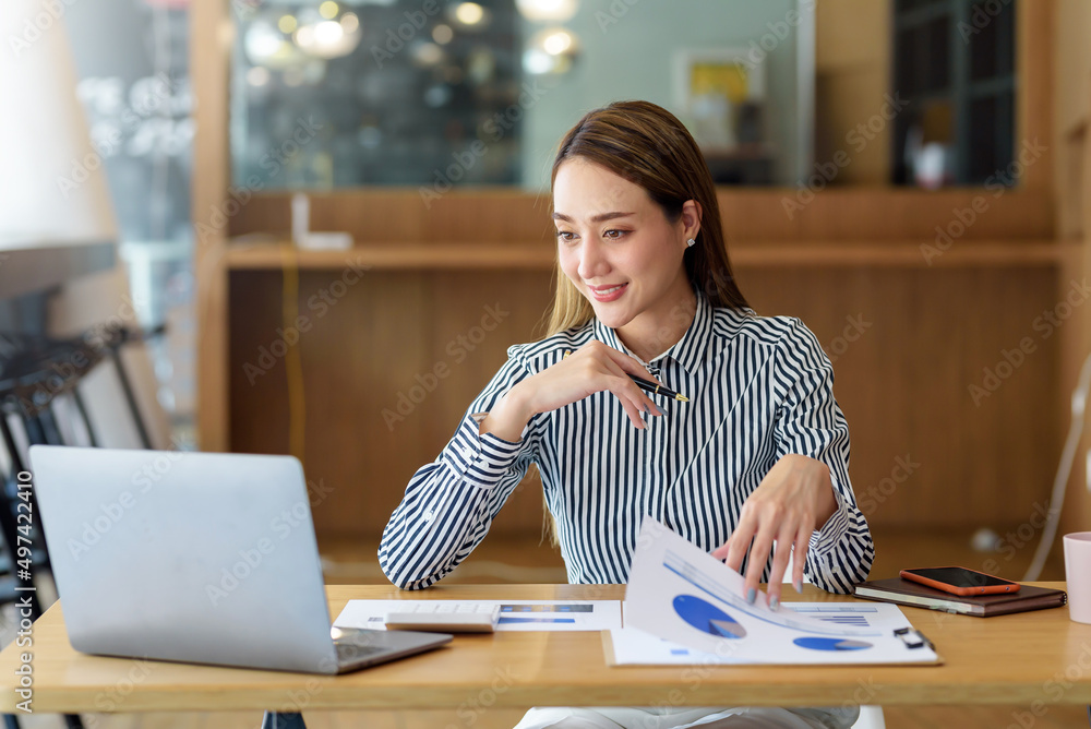 Beautiful Asian business woman sitting working on laptop in office. Beautiful Asian business woman sitting working on laptop in office.