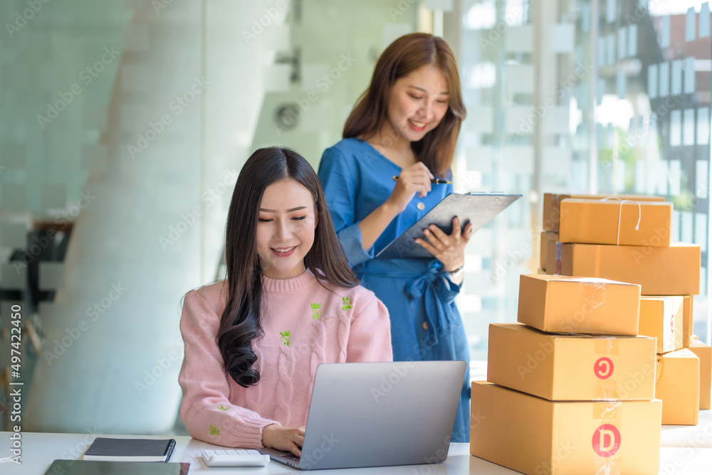 Two beautiful young Asian business owner woman prepare parcel box and check online orders of product for deliver to customer. Shopping Online concept. Two beautiful young Asian business owner woman prepare parcel box and check online orders of product for deliver to customer. Shopping Online concept.