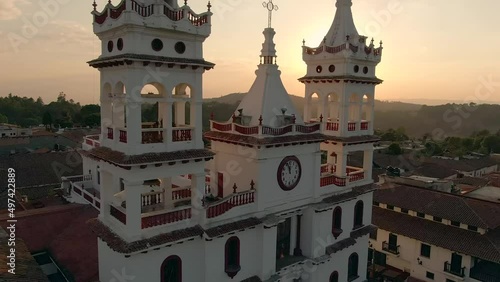 San Cristobal Church Bell Tower With Clock On Front Facade At Sunset In Mazamitla, Jalisco, Mexico. - aerial ascend photo