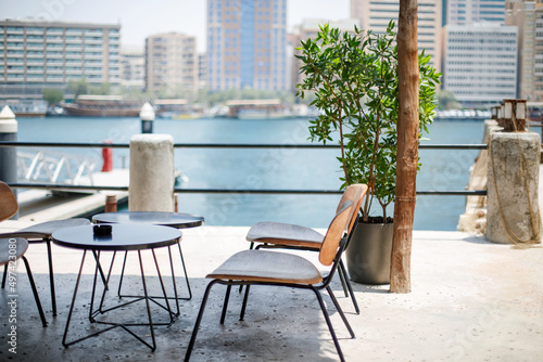 An outdoor cafe overlooking the Dubai Creek water canal with the Deira district in the background © Sviatlana