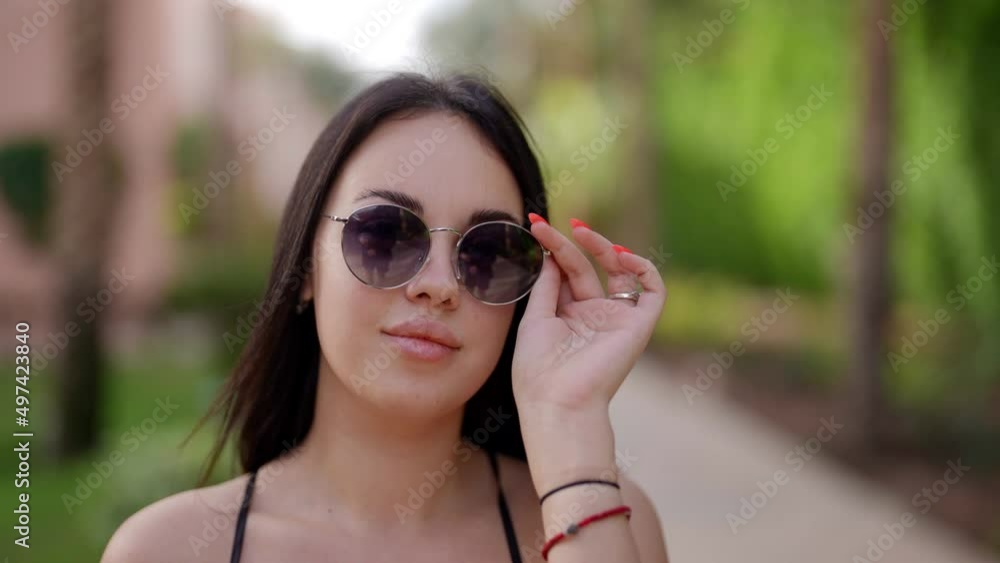 sexy young woman with full lips is walking in summer, correcting sunglasses and looking at camera sexy young woman with full lips is walking in summer, correcting sunglasses and looking at camera