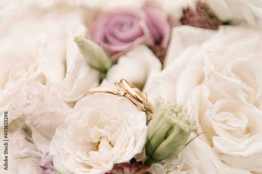 Obraz premium Wedding wedding rings on a bouquet of flowers, soft focus