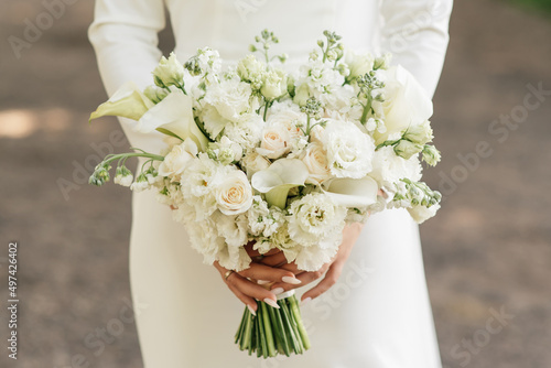 Obraz na płótnie A luxurious wedding bouquet with white roses, carnations and koalas in the hands of the bride w salonie