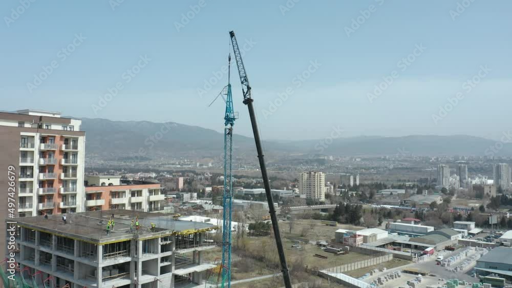 An aerial jib shot moving downwards of a crane that's being assembled from the ground-up. Another mobile crane is used to assist. The tower rises from the base and builds itself one section at a time. An aerial jib shot moving downwards of a crane that's being assembled from the ground-up. Another mobile crane is used to assist. The tower rises from the base and builds itself one section at a time.