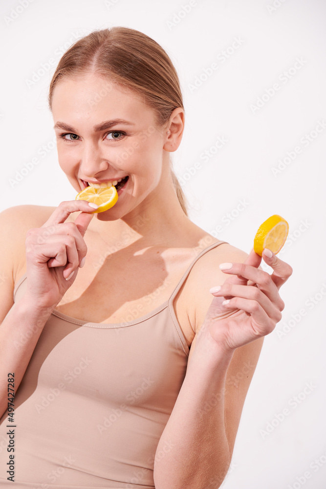 beautiful blonde woman laying on a white wooden background next to slices of lemon, having a slice of lemon on the eyes and smiling beautiful blonde woman laying on a white wooden background next to slices of lemon, having a slice of lemon on the eyes and smiling