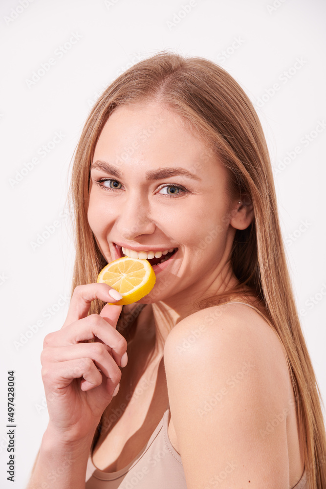 beautiful blonde woman laying on a white wooden background next to slices of lemon, having a slice of lemon on the eyes and smiling beautiful blonde woman laying on a white wooden background next to slices of lemon, having a slice of lemon on the eyes and smiling