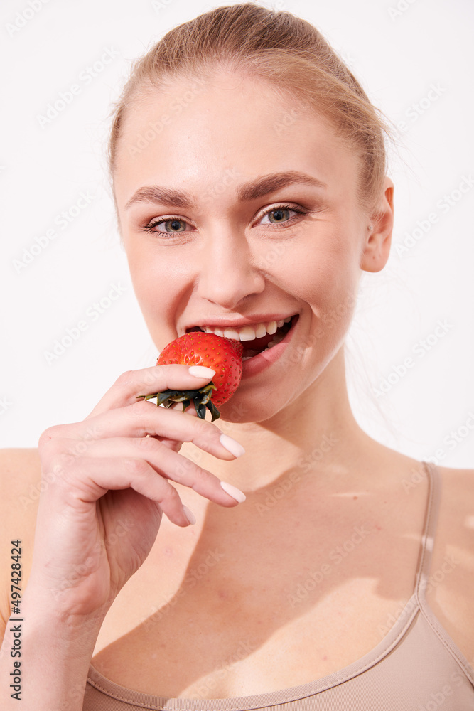 A creative portrait of a beautiful girl holding with one hand a juicy strawberry near her lips with temptation. A creative portrait of a beautiful girl holding with one hand a juicy strawberry near her lips with temptation.