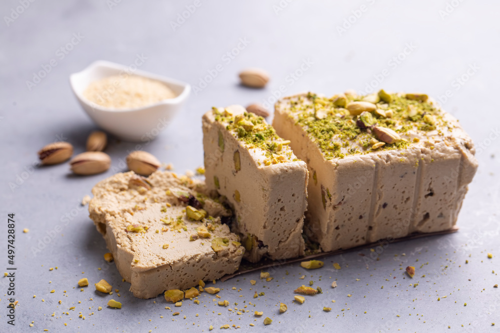 Sesame halva with pistachios on grey background. Top view. Copy space. Traditional middle eastern sweets. Jewish, turkish, arabic national dessert. Turkish delight. Sesame halva with pistachios on grey background. Top view. Copy space. Traditional middle eastern sweets. Jewish, turkish, arabic national dessert. Turkish delight.