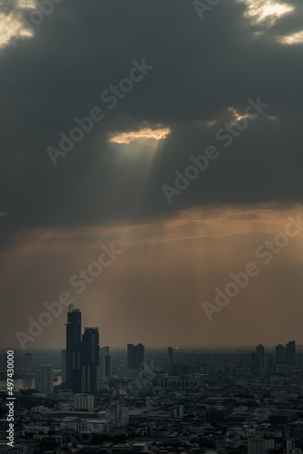 The sun s rays passing through the clouds and illuminate skhining down over the skyscraper of bangkok. Selective focus on clouds.