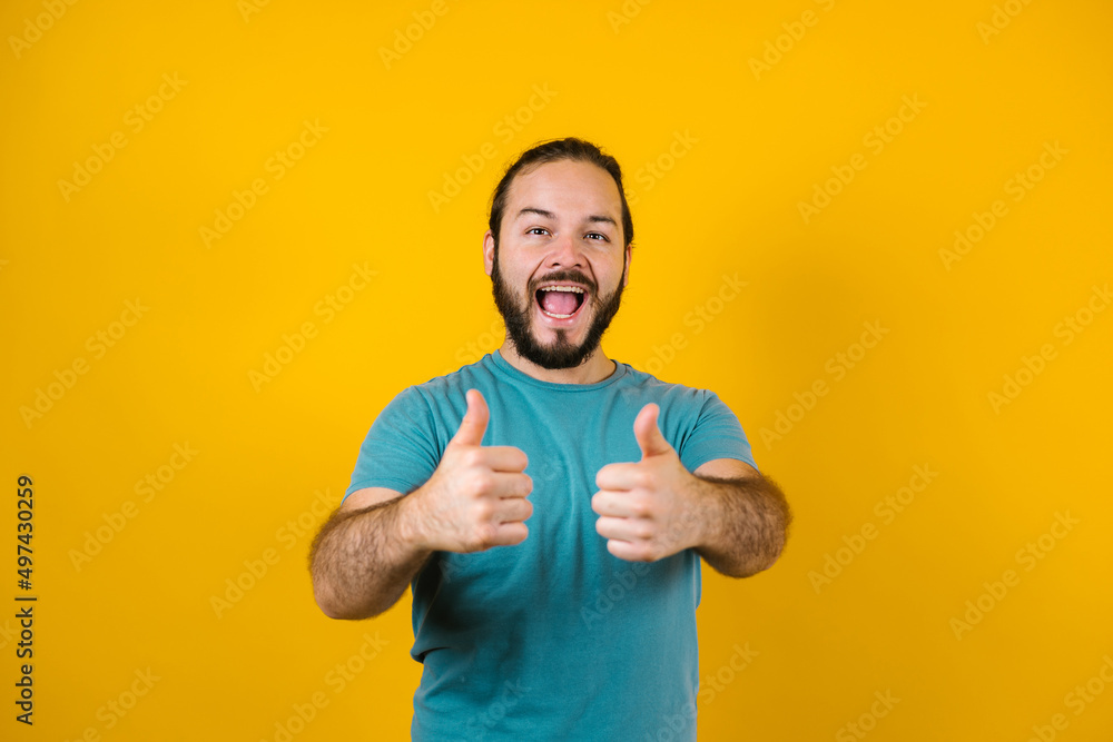 portrait of young hispanic man with copy space and thumbs up on yellow background in Mexico Latin America portrait of young hispanic man with copy space and thumbs up on yellow background in Mexico Latin America