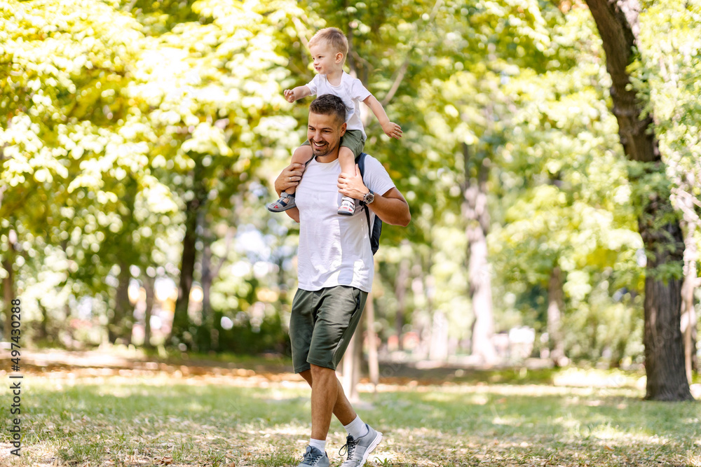 Playful father and son having piggyback ride in forest on earth's day. Playful father and son having piggyback ride in forest on earth's day.