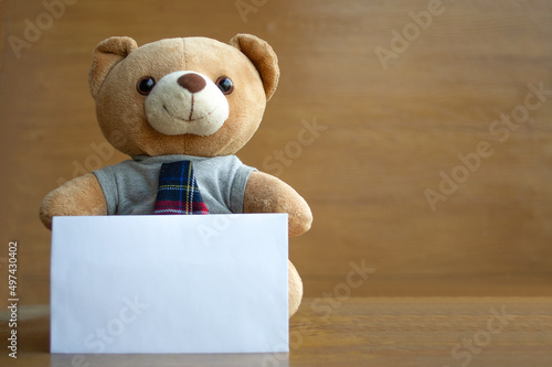 Brown teddy bears and white blank paper on brown wooden background. Birthday or anniversary greeting card concept.
