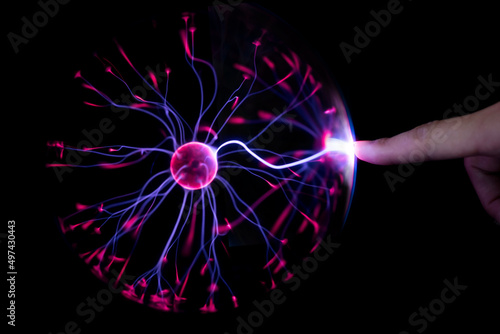 Obraz na plátne Finger touching plasma light ball on black background