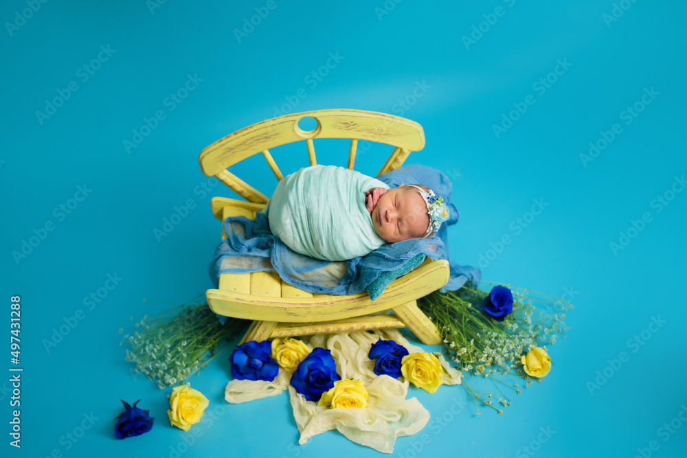 Ukrainian newborn in the studio patriotic blue yellow colors during the war in Ukraine 2022. A little baby, girl sleeps on a chair Ukrainian newborn in the studio patriotic blue yellow colors during the war in Ukraine 2022. A little baby, girl sleeps on a chair