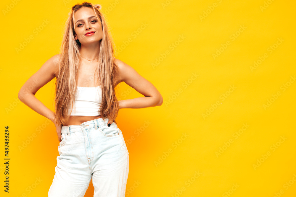 Portrait of young beautiful smiling blond female in trendy summer clothes. Sexy carefree woman posing near yellow wall in studio. Positive model having fun indoors. Cheerful and happy Portrait of young beautiful smiling blond female in trendy summer clothes. Sexy carefree woman posing near yellow wall in studio. Positive model having fun indoors. Cheerful and happy