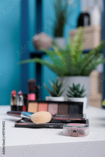 Cosmetics product standing on white table in studio with blue backgrounnd. Empty room waiting for social media content creator to recording podcast. Make up tutorial vlog concept