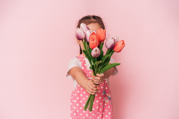 Little Asian girl with bouquet of tulips in front of pink background. happy mother's day