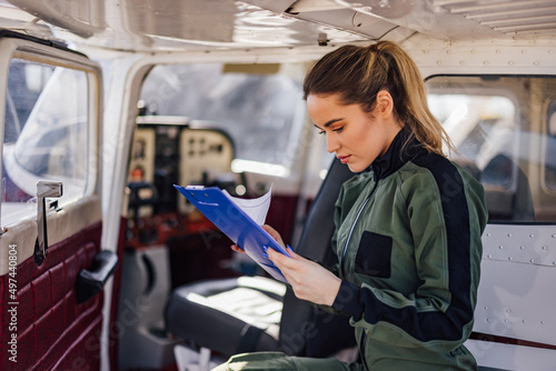 Relaxed Caucasian woman pilot, checking her blue notebook.