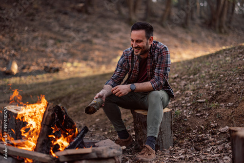 Photo of a man enjoying around the campfire, sitting alone.