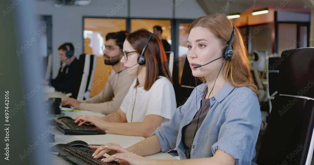 Portrait of happy Caucasian beautiful woman in headset sitting in front of computer and smiling. Call center. Joyful female support worker chatting with customer or client. Job in sales online. Portrait of happy Caucasian beautiful woman in headset sitting in front of computer and smiling. Call center. Joyful female support worker chatting with customer or client. Job in sales online.