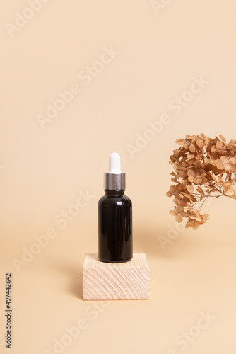 Wooden podium or pedestal with a dropper bottle of cosmetics oil or serum. Neutral beige monochrome skin care concept