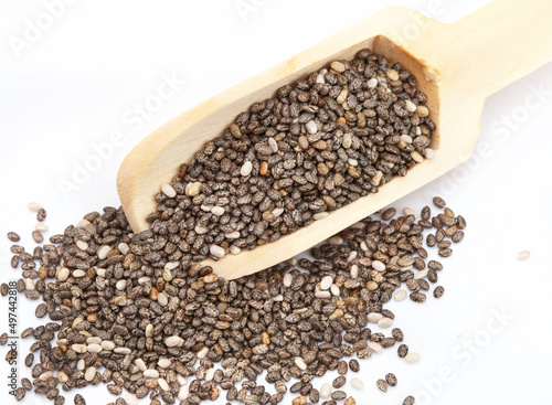 wooden scoop with Chia seeds, a superfood on light neutral surface