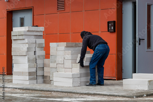 Wallpaper Mural A man carries foam concrete blocks to the construction site, Preparing for construction work. The erection of walls in a residential building. Torontodigital.ca