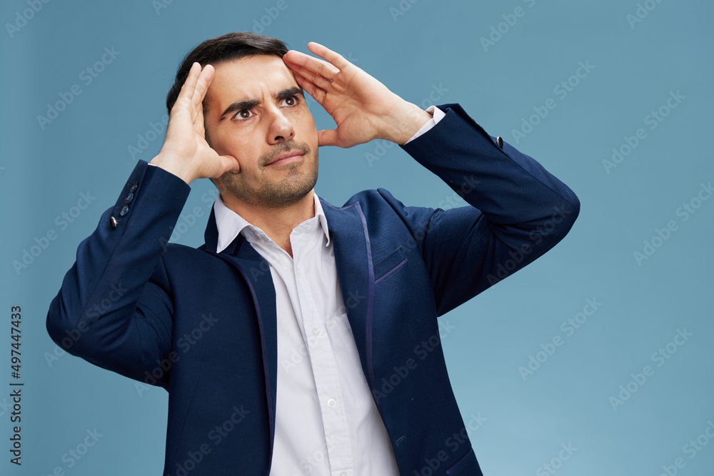 a man looks into the distance holding his hands on his face in a business suit work career growth isolated background. Copy space a man looks into the distance holding his hands on his face in a business suit work career growth isolated background. Copy space