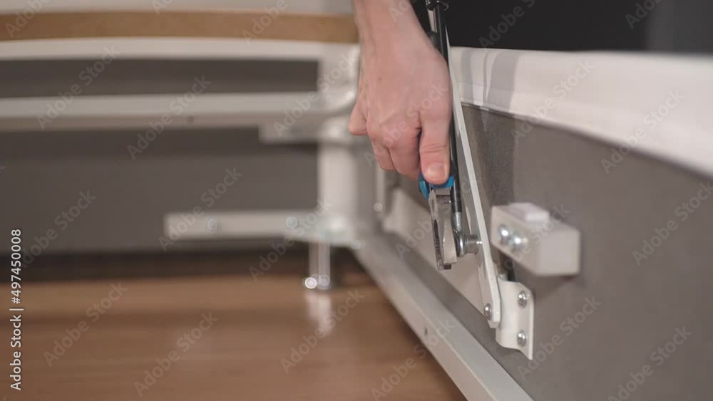 a man with a tool tightens a nut while assembling furniture a man with a tool tightens a nut while assembling furniture