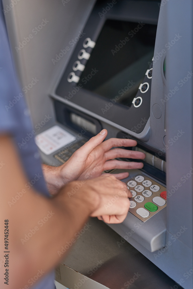 Keeping his pin code a secret. Cropped shot of a man entering his secret pin code at an ATM. Keeping his pin code a secret. Cropped shot of a man entering his secret pin code at an ATM.