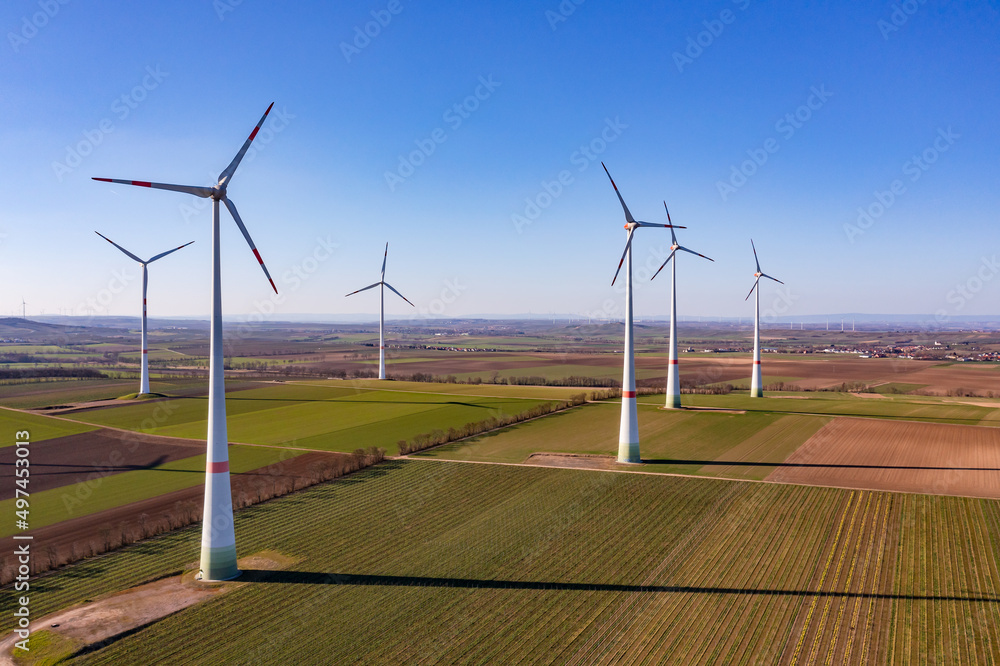Wind farm with tall wind turbines in rural landscape as aerial shot