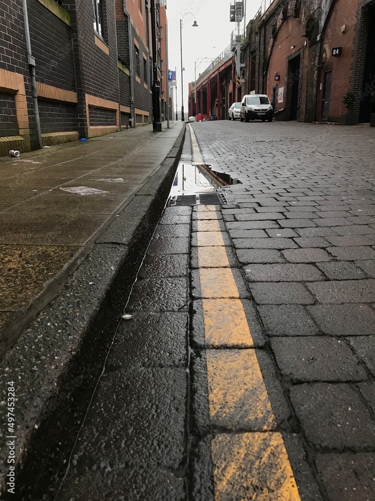 Low angle view of a city street with parked cars and no people. Selective focus image taken in Manchester England. 