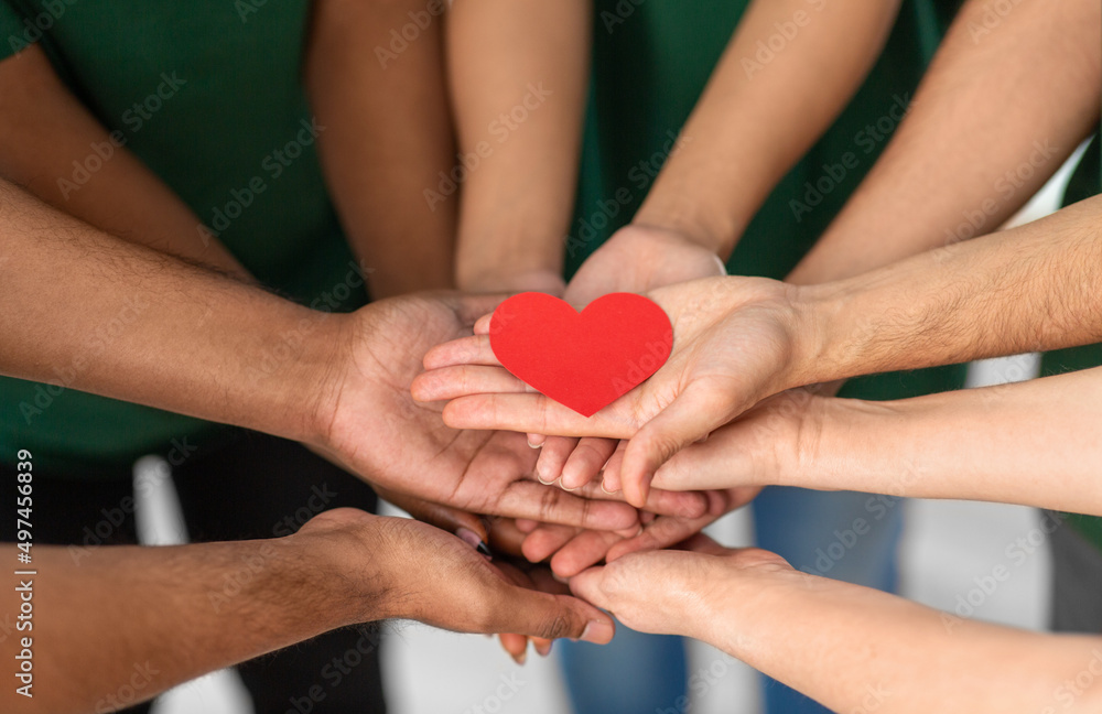 charity, support and volunteering concept - close up of volunteers's hands holding red heart at distribution or refugee assistance center charity, support and volunteering concept - close up of volunteers's hands holding red heart at distribution or refugee assistance center
