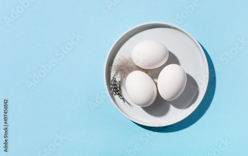 Easter white eggs and feathers on blue background.