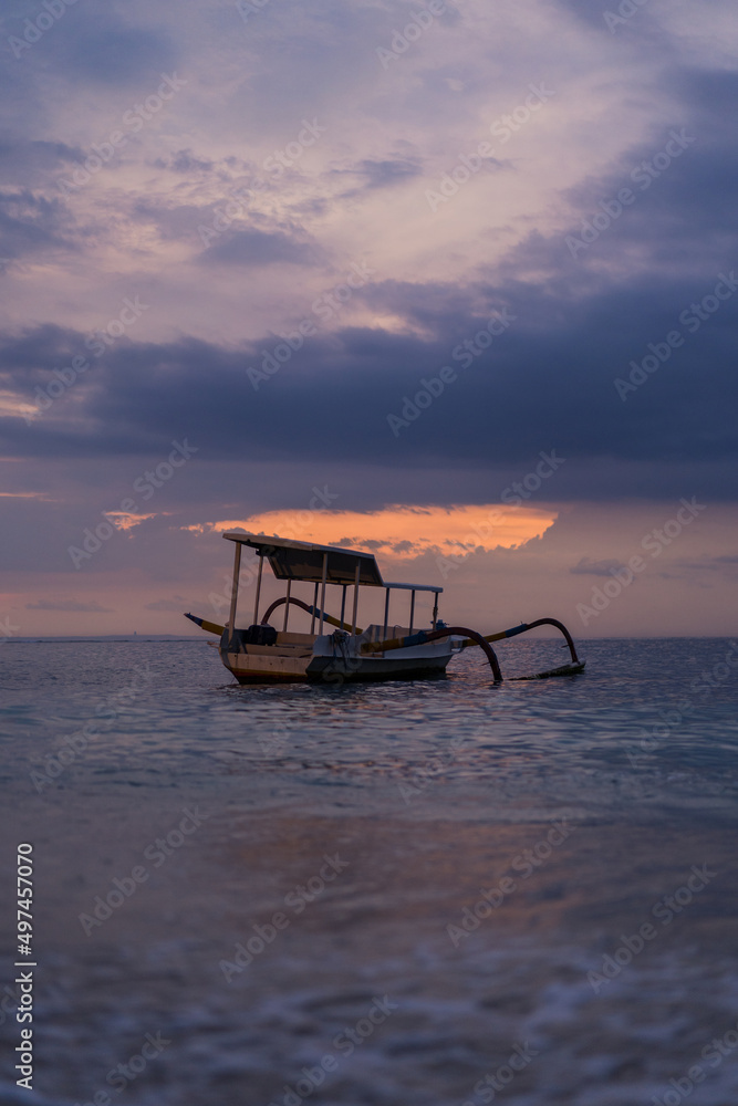 Balinese authentic fishing boat in the water at sunset. Background.