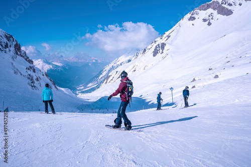 Snowboarders and skiers standing on snowy mountain slope at winter resort