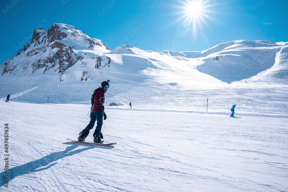 Young snowboarder sliding down snowy slope on mountain at winter resort