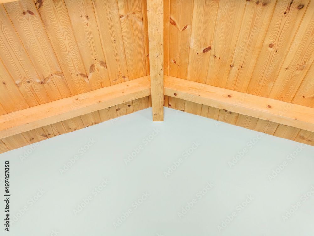 Attic gable ceiling. Wooden mansard construction. Traditional mediterranean house. Greek villa interior. Light blue turquoise painted plaster wall and natural pine wooden roof in room. Attic gable ceiling. Wooden mansard construction. Traditional mediterranean house. Greek villa interior. Light blue turquoise painted plaster wall and natural pine wooden roof in room.