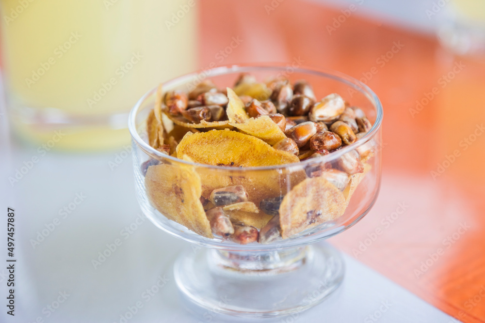 Small bowl of toasted salted corn kernels and banana chips in a Peruvian bar Small bowl of toasted salted corn kernels and banana chips in a Peruvian bar